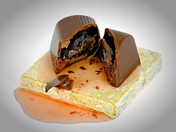 bonbom cortado feito de chocolate escuro preenchido com cereja e licor em uma base de mármore - Foto, Imagem