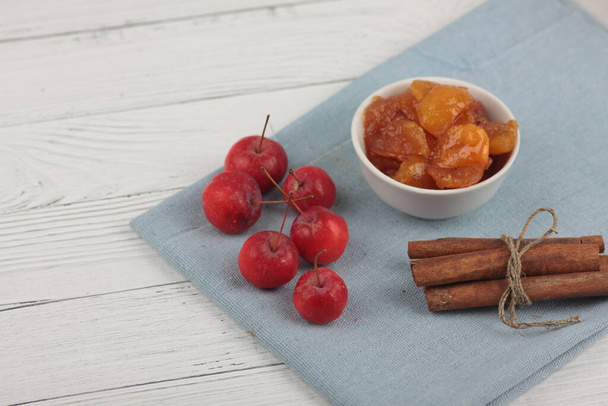 a bowl of apple jam, red apples and cinnamon sticks on blue napkin on white wooden background flat lay. Image contains copy space - Photo, Image