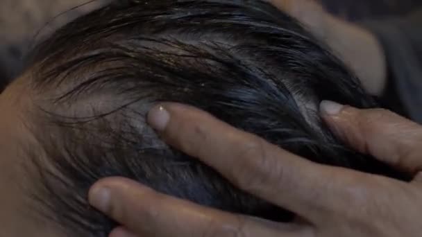 Fiatal ázsiai nő olajat kap a fejbőrébe és a hajába. Lezárva, oldalnézet, közelkép - Felvétel, videó