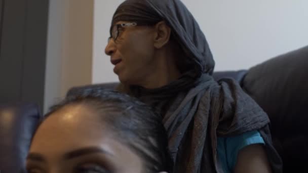 Mujer musulmana usando Hijab Masajeando el cabello de una joven hembra sentada en el interior. Ángulo bajo, bloqueado - Imágenes, Vídeo