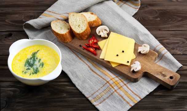 Chutná sýrová polévka v talíři se lžící a dřevěnou deskou. - Fotografie, Obrázek