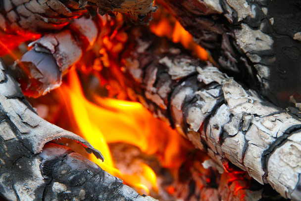 Glowing embers in hot red color, abstract background. The hot embers of burning wood log fire. Firewood burning on grill. Texture fire bonfire embers. - Foto, Bild