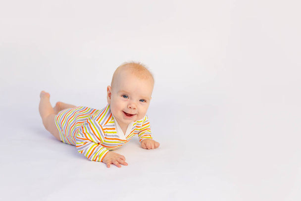 pequena menina sorridente 6 meses de idade encontra-se em um fundo branco isolado em um bodysuit brilhante, espaço para texto. Uma criança feliz e saudável. - Foto, Imagem