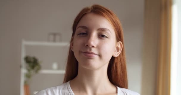 Portrét krásné mladé ženy s rudými vlasy v bílých šatech, dívající se do kamery a okouzlující úsměv. Úspěšná studentka, která pózuje sama. Snímek hlavy sebevědomé zrzky teen dáma - Záběry, video