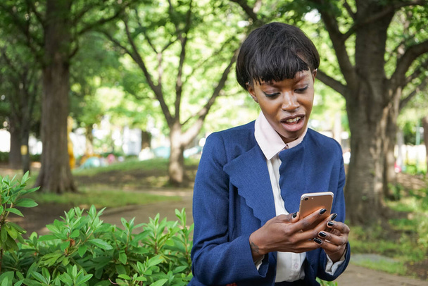 african woman looking at smartphone screen with confused face - Photo, Image