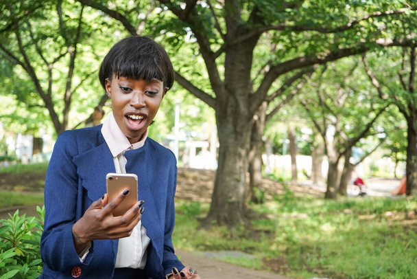 Αφρικανή γυναίκα που κοιτάζει την οθόνη smartphone με συγκεχυμένο πρόσωπο - Φωτογραφία, εικόνα