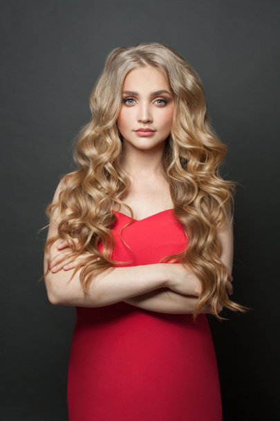 Pretty blonde hair woman wearing red dress standing with crossed arms on black background - Φωτογραφία, εικόνα