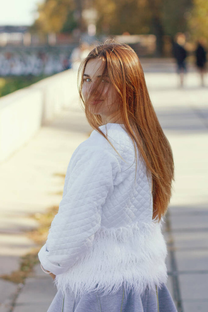 Πορτρέτο του πανέμορφο ευτυχισμένη κοπέλα σε γκρι φόρεμα και λευκό σακάκι στο ηλιοβασίλεμα. - Φωτογραφία, εικόνα