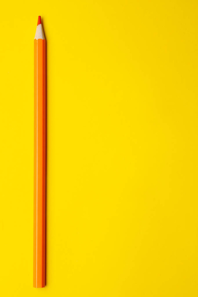vertical orange sharp wooden pencil on a bright yellow background, isolated, copy space, mock up - Foto, Imagem