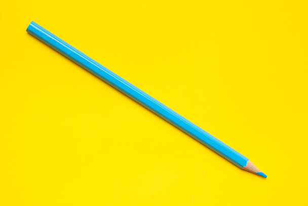 diagonal blue sharp wooden pencil on a bright yellow background, isolated, copy space, mock up - Φωτογραφία, εικόνα