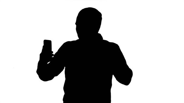 Silhouette Young blogger recording video on his phone while walk - Photo, image