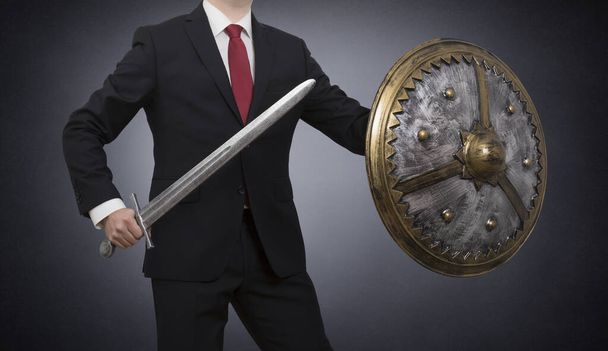 Businessman with sword and shield on dark background with clipping path. Business protection concept. - Foto, Bild