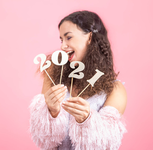 木製番号2021ピンクのスタジオの背景に美しい陽気な女の子の手の中に、幸せな新年のコンセプト - 写真・画像