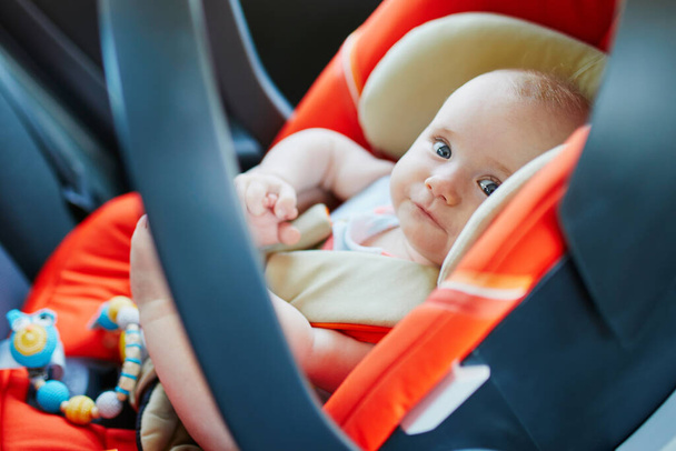 Adorable baby girl in modern car seat. Little kid traveling by car. Child safety on the road. Trip with an infant. - Foto, Imagem