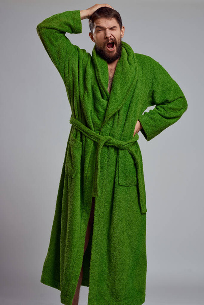 Vista close-up de um homem barbudo em um manto verde em um fundo claro vista cortada - Foto, Imagem