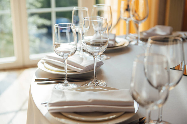 Luxurious restaurant. Luxurious interior, white tables, serving dishes and glasses for guests - 写真・画像