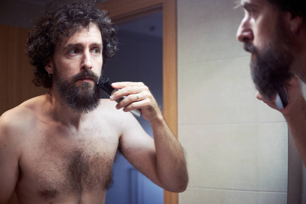 Homem hispânico de meia-idade cortando sua barba - Foto, Imagem