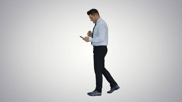 Man walking looking on phone and making win gesture on gradient - Photo, image