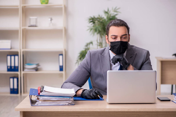 Joven empleado masculino en la oficina durante enfermedad pandémica - Foto, Imagen