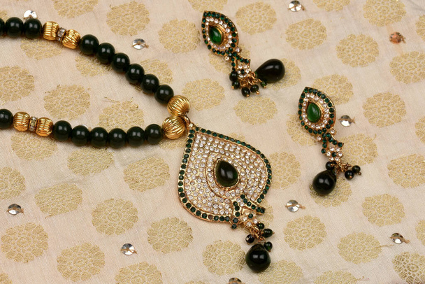 Joyería tradicional india colocada en tela con pendiente de piedra verde y earrings.diamond, joyería femenina de lujo, joyería tradicional india, arete de diamantes, joyería de boda de oro nupcial - Foto, imagen