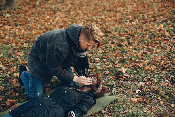 Mies syksyllä puistossa auttaa afrikkalainen tyttö - Valokuva, kuva