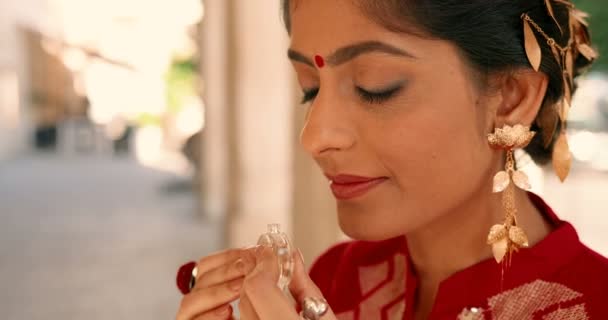 額に赤い点を持つヒンズー教の若い美しい女性と伝統的な衣装で香水の屋外の匂いを閉じます。ストリートでスタイリッシュな魅力的な女性の匂いや香りを嗅ぐ。美しさの概念。香水 - 映像、動画