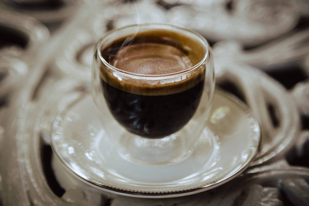 Hot black coffee on outdoor table in a transparent glass.Selective focus - Fotografie, Obrázek