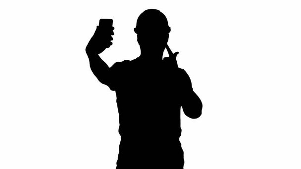 Silhouet Lachende knappe jonge bouwer die selfie maakt met maffia - Foto, afbeelding