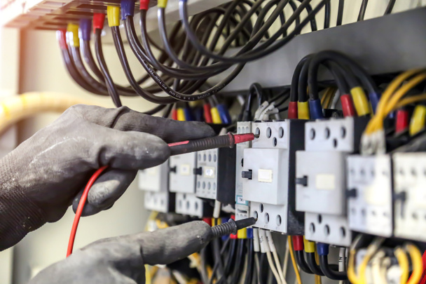 Ingeniero eléctrico que utiliza equipos de medición para comprobar el voltaje de corriente eléctrica en el disyuntor y el sistema de cableado de cable para el mantenimiento en la placa de distribución de energía principal. - Foto, Imagen