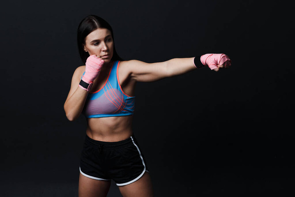 スポーツマンムエタイ女性ボクサーポーズでトレーニングスタジオに黒の背景. - 写真・画像
