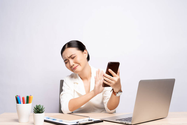 Retrato de mujer triste utiliza teléfono inteligente en la oficina aislado sobre el fondo - Foto, imagen