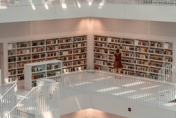 Stuttgart, Alemania - Aug 1, 2020 - Bibliotecario clasificando libros en la biblioteca pública de Stadtbibliothek con luz solar por la mañana - Foto, Imagen