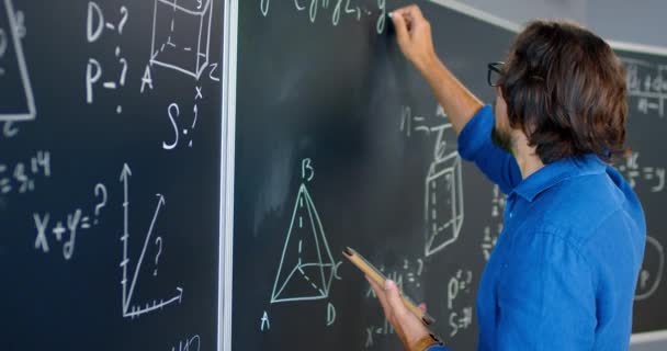 Hátul a fehér férfi tanár szemüvegben áll a fedélzeten az osztályteremben, és fizika vagy geometria törvényeket mond az osztálynak. Iskolai koncepció. Oktató matematika lecke. Vissza az előadóra. - Felvétel, videó