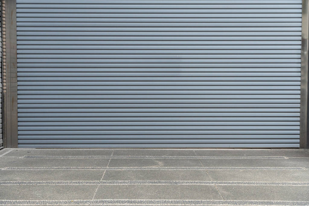 Un primer plano de puerta automática de rodillo de metal utilizado en fábrica, almacenamiento, garaje y almacén industrial. La lámina de metal corrugado y plegable ofrece ahorro de espacio y proporciona sensación urbana y rústica - Foto, imagen