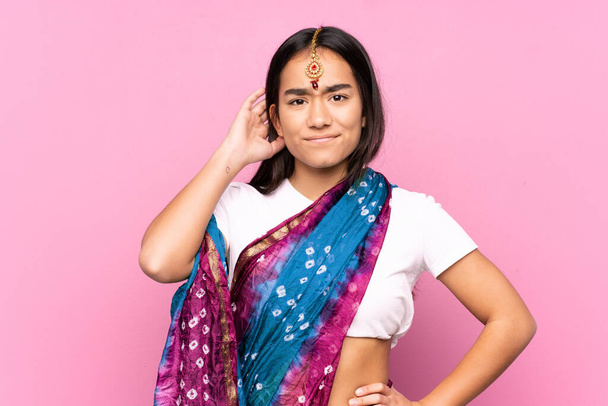 Mladá indická žena se sari nad izolovaným pozadím s pochybnostmi - Fotografie, Obrázek