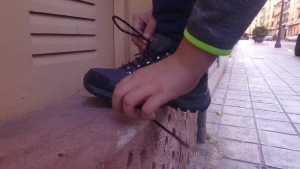 poika sitoo kengännauhat lenkkareihinsa - Materiaali, video
