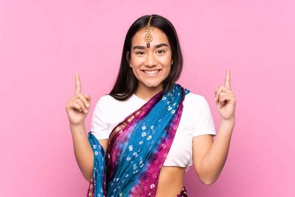 Молодая индийская женщина с сари на изолированном фоне указывает на отличную идею - Фото, изображение