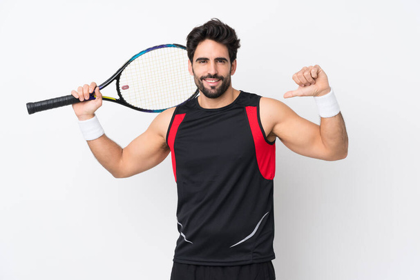 Молодой красивый мужчина с бородой на изолированном белом фоне играет в теннис и гордится собой - Фото, изображение