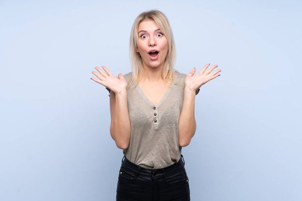 Young blonde woman over isolated blue background with surprise facial expression - Foto, Bild
