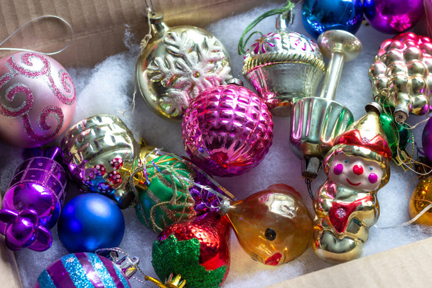 Una caja con viejos juguetes de Navidad de vidrio soviético desempaquetados en anticipación de las vacaciones. - Foto, imagen