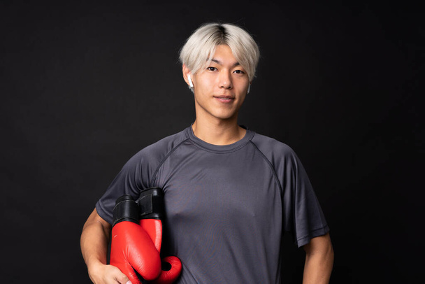 Jonge aziatische sport man over geïsoleerde zwarte achtergrond - Foto, afbeelding