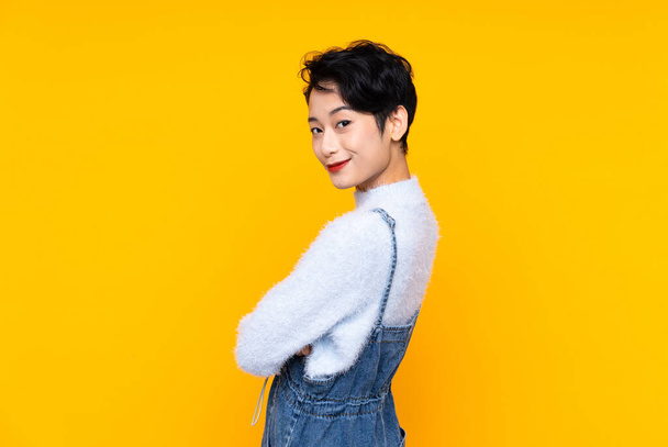 Giovane ragazza asiatica in tuta sopra isolato giallo sfondo ridere - Foto, immagini