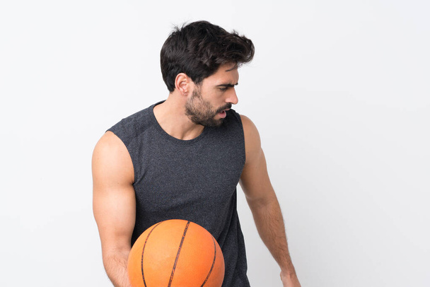 Fiatal jóképű férfi szakáll felett elszigetelt fehér háttér játszik kosárlabda - Fotó, kép