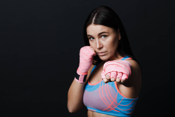 Sportsman muay thai női bokszoló pózol gyakorló stúdió fekete háttér. - Fotó, kép