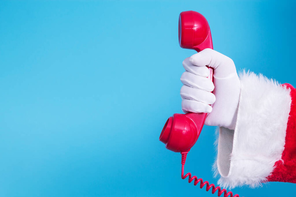 Santa Claus holding red phone with blue background - Photo, image