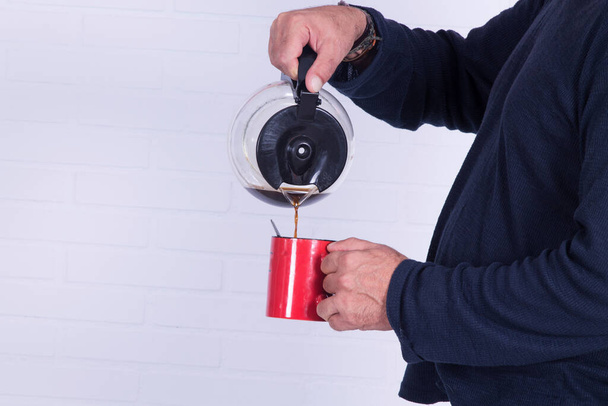 man pouring himself a cup of coffee with the coffee maker - Photo, image