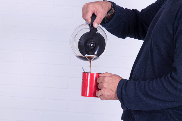 man pouring himself a cup of coffee with the coffee maker - Foto, Imagen