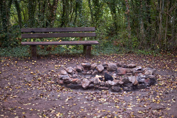 Cheminée en pierre photographiée avec un banc en bois dans la nature. - Photo, image