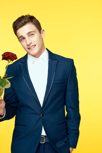 Gentleman in classic suit on yellow background with red rose romance  - Фото, изображение