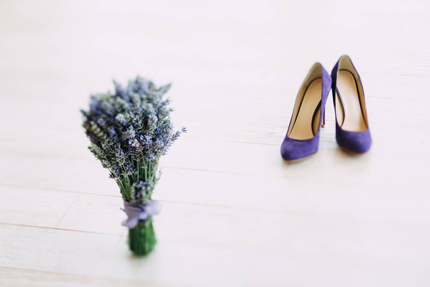 Un ramo de zapatos de tacón alto de color púrpura lavanda y mujer en una textura de madera blanca. - Foto, imagen